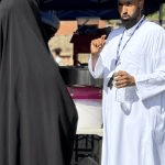 An organizer or staff member speaking with a guest near a food machine under a tent canopy_jfif