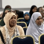 Women wearing headscarves seated in the audience, watching the proceedings during the event_jfif